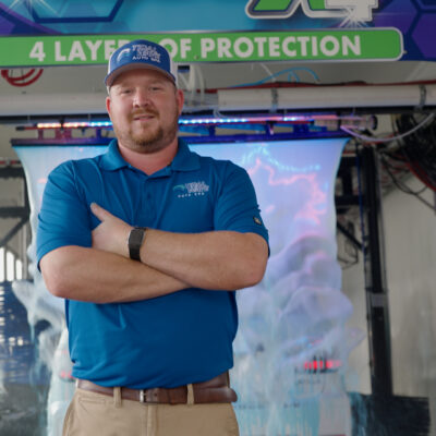 Confident Tidal Wave Auto Spa Houston team member standing in an express car wash tunnel