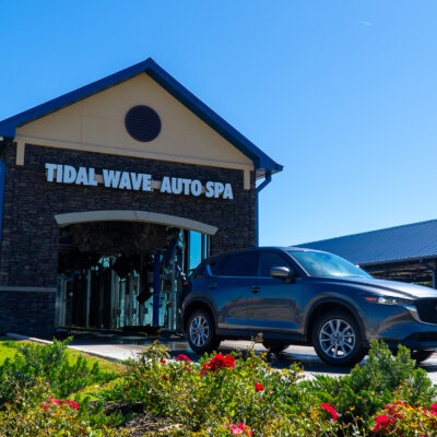 Confident Tidal Wave Auto Spa team member standing in an express car wash tunnel